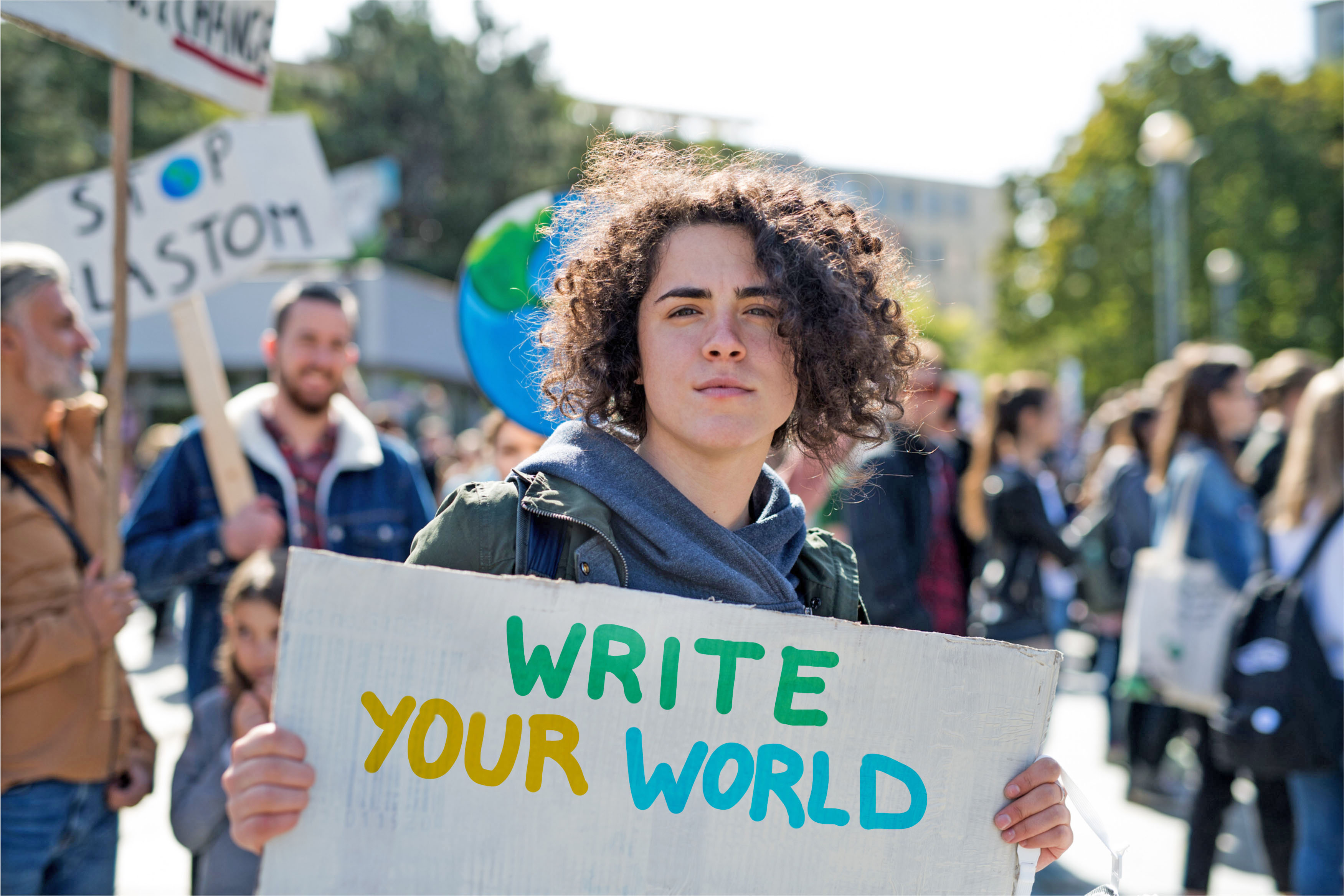 Jugendlicher hält Plakat mit Aufschrift "write your world"